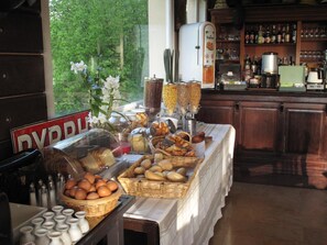Een ontbijtbuffet met verschillende soorten brood, gebak en eieren.