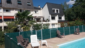 Una piscina con sillas de descanso y una valla verde.