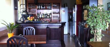 A bar area with wooden furniture, a counter with bottles, and a refrigerator.