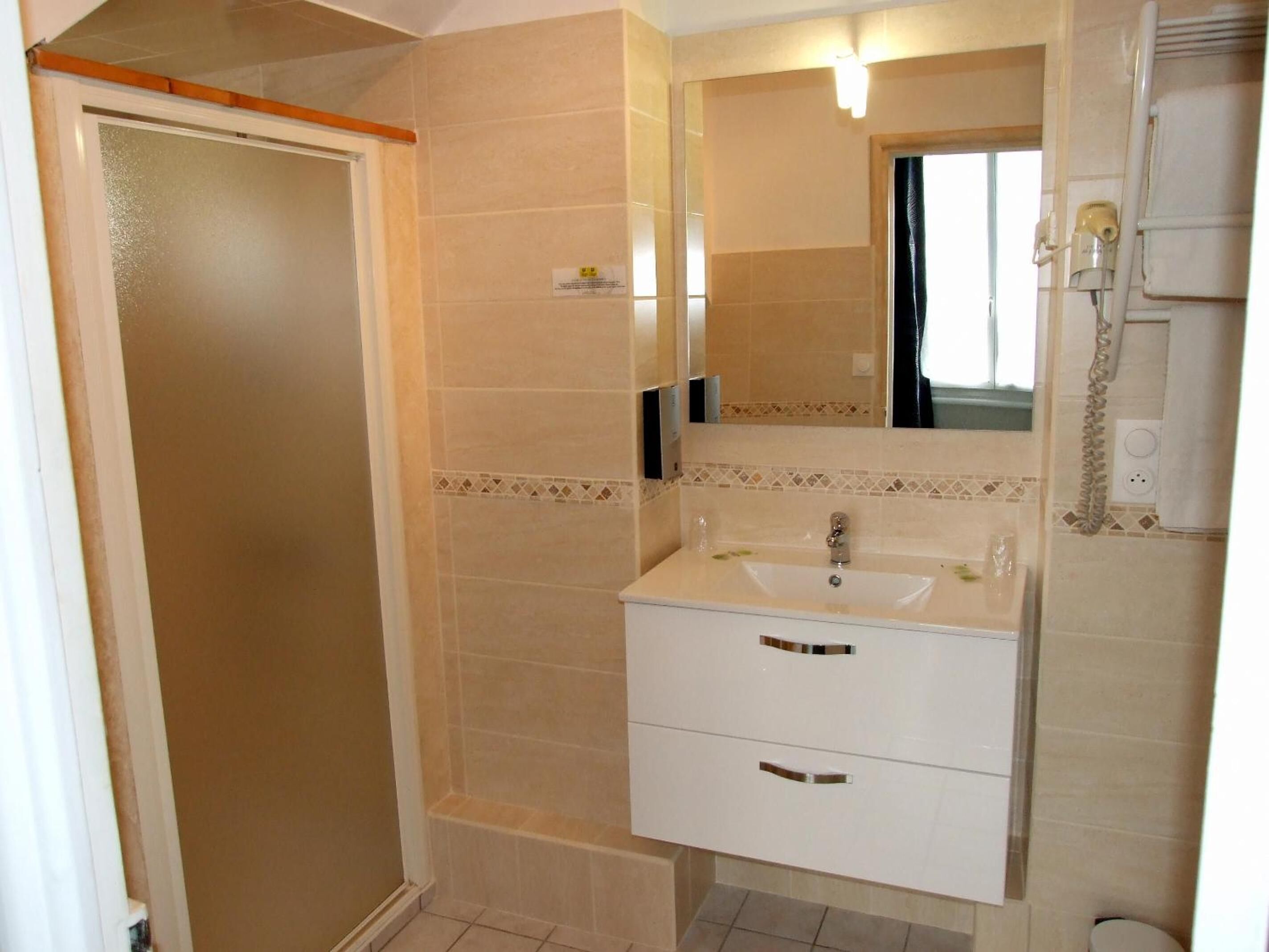 Een badkamer met een wit wastafelmeubel, spiegel en handdoekhouder.