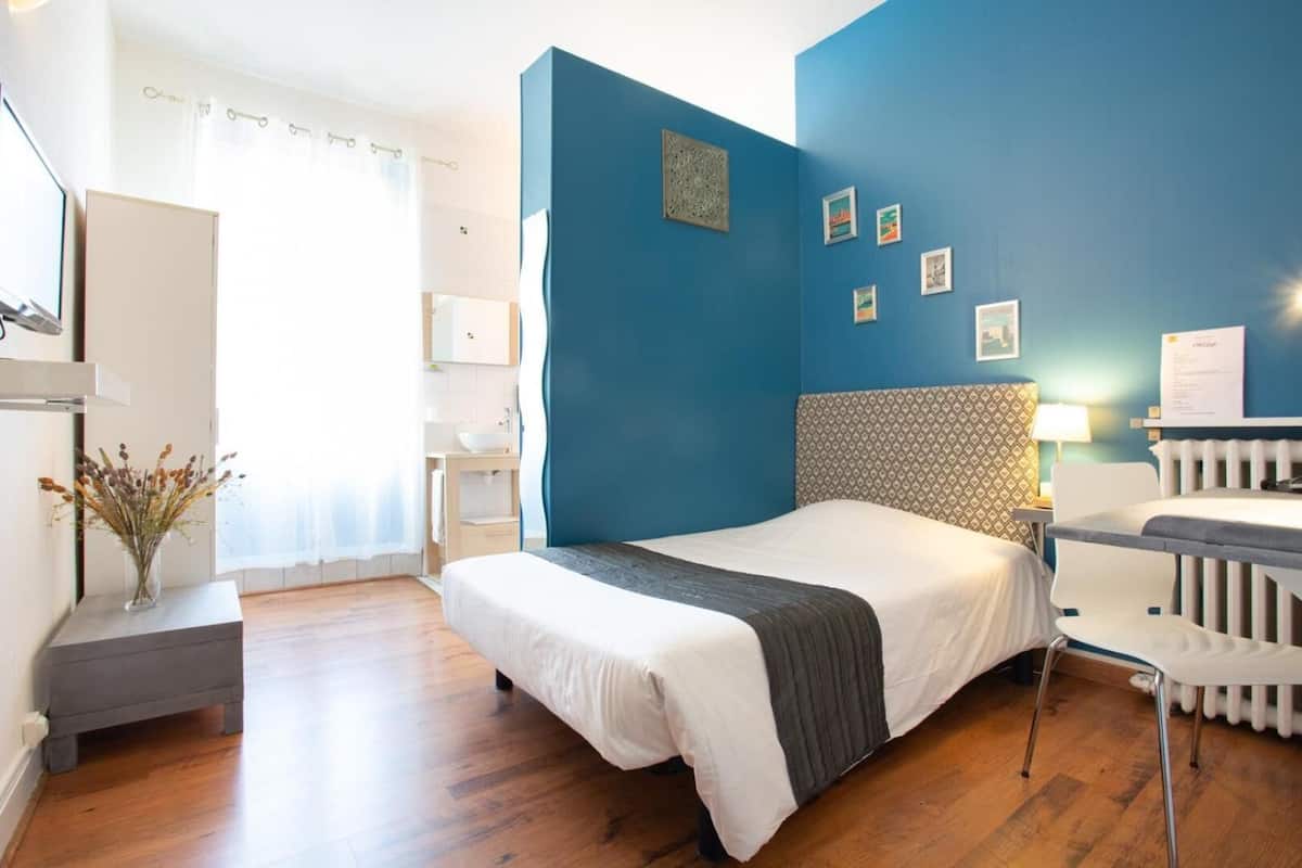 Une chambre d’hôtel moderne, dotée d’un grand lit, d’un bureau et offrant une vue sur la ville.