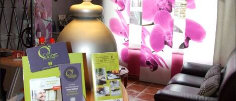 A room with a large lamp, brochures on a table, and a window with pink flowers.
