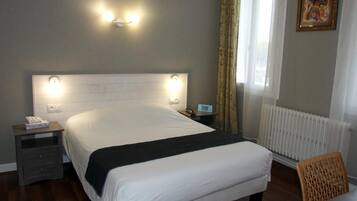 A hotel room with a large bed, bedside tables, a chair, and a painting on the wall.