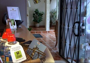A hotel reception area with a counter, a water dispenser, a basket with a card, and a security gate. - Hôtel l'Occitan (Gaillac)