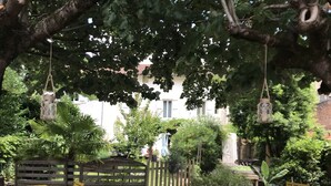 A garden patio with yellow chairs and tables, surrounded by trees and a wooden fence. - Hôtel l'Occitan (Gaillac)
