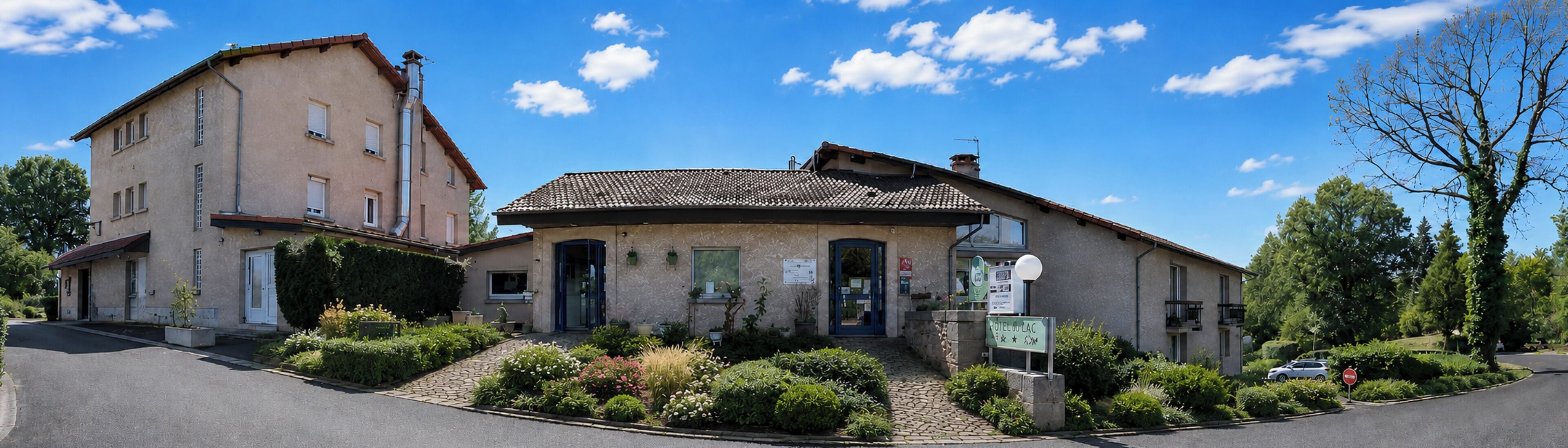 A two-story building with a tiled roof, a front entrance, and a sign indicating it is a hotel.