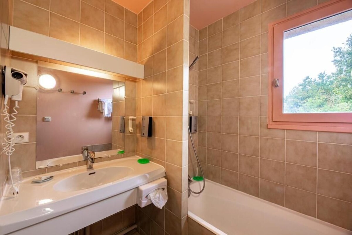 A bathroom with a sink, mirror, and shower.