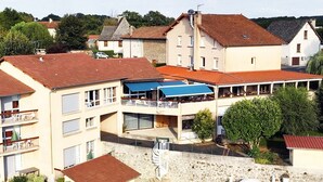 A multi-story hotel with a swimming pool, outdoor seating area, and a covered patio. - Hôtel du Lac (Lacapelle-Viescamp)