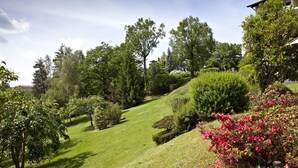 A landscaped garden with various trees and shrubs, a well-maintained lawn, and a building in the background. - Hôtel du Lac (Lacapelle-Viescamp)