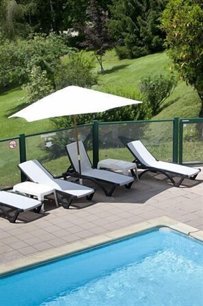 A poolside area with lounge chairs and a white umbrella. - Hôtel du Lac (Lacapelle-Viescamp)