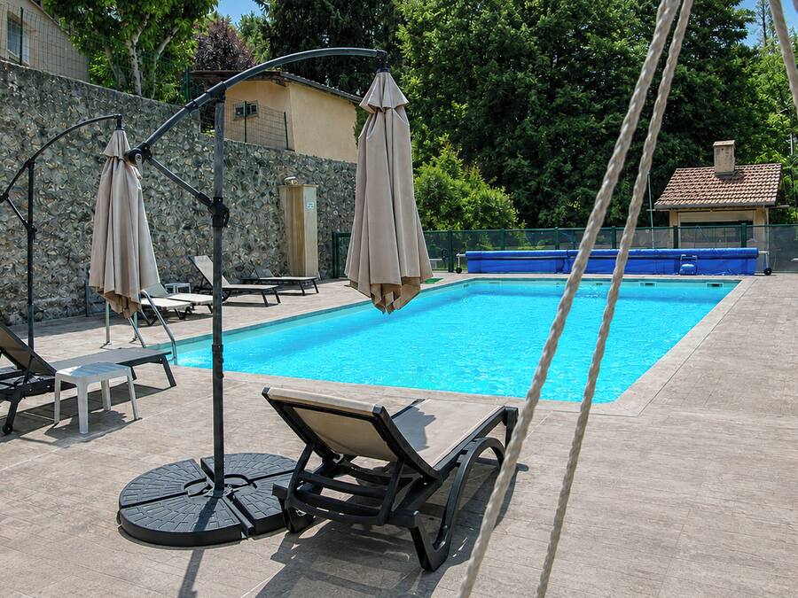 Una piscina al aire libre, sombrillas, sillones reclinables de piscina