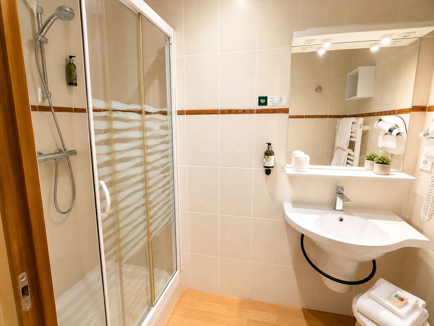 Ein modernes Badezimmer mit einer Duschkabine aus Glas, einem weißen Waschbecken und einem Spiegel darüber.
