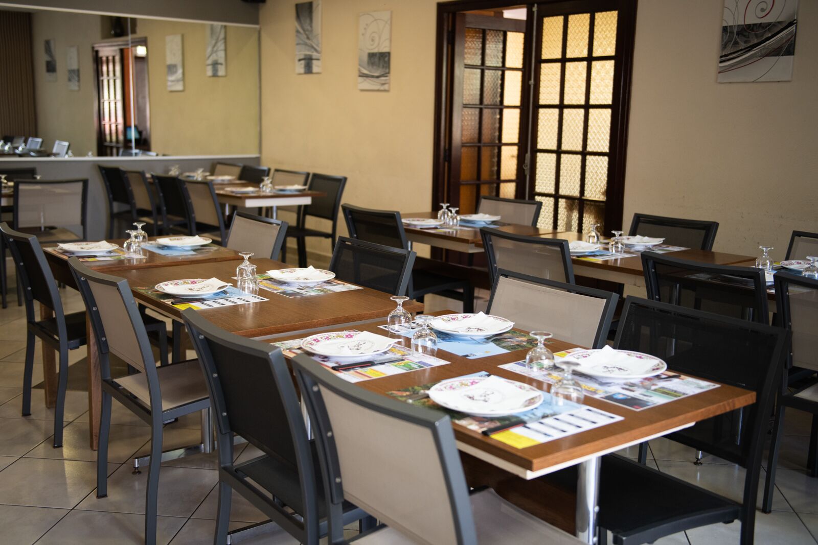 A conference room with multiple tables set for a meeting, equipped with chairs, plates, glasses, and documents.