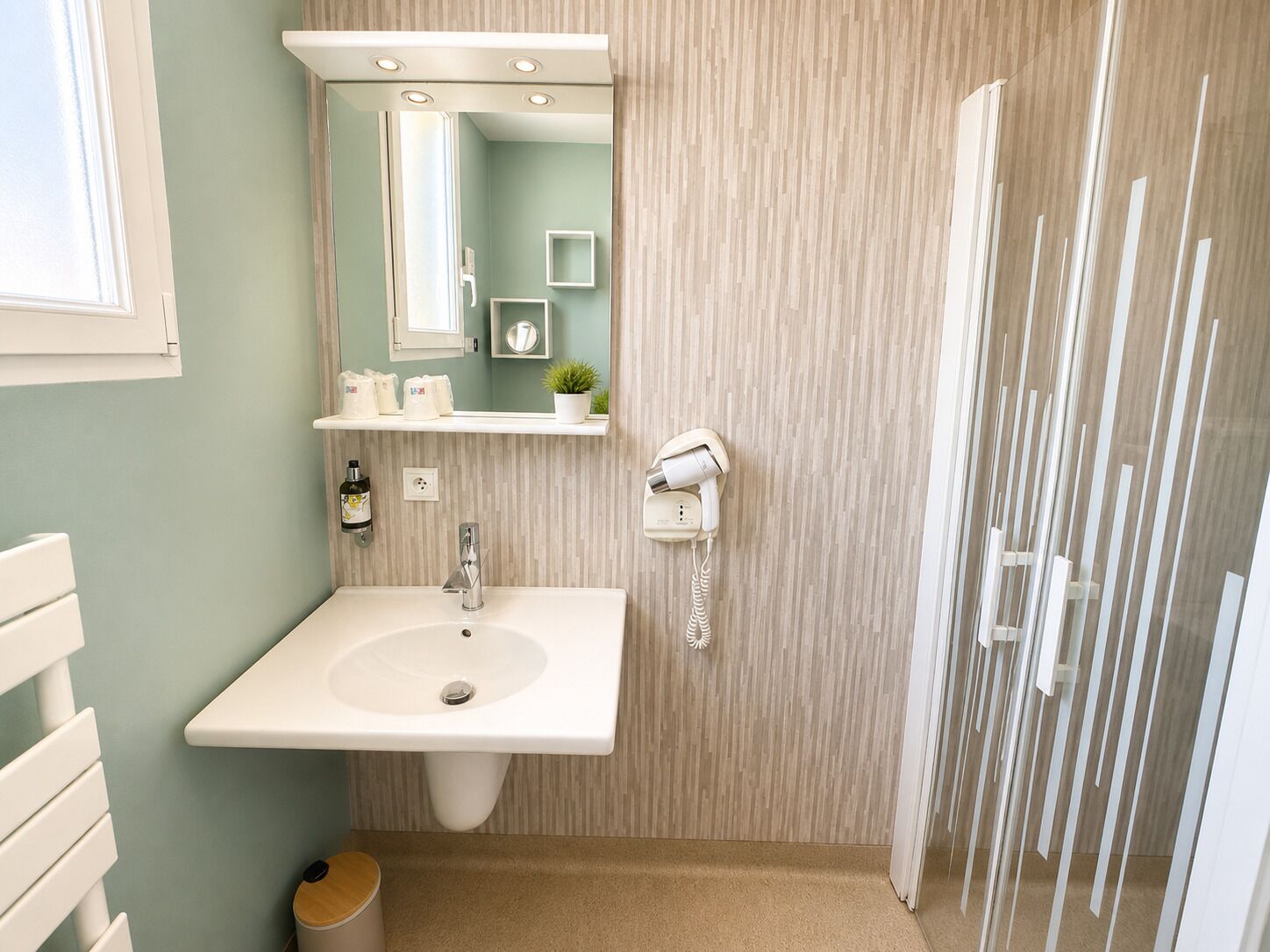 A bathroom with a sink, mirror, towel rack, and a hairdryer on the wall.
