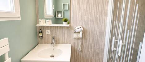A bathroom with a sink, mirror, towel rack, and a hairdryer on the wall.