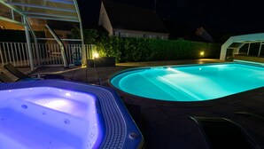 A swimming pool with a hot tub and lounge chairs.