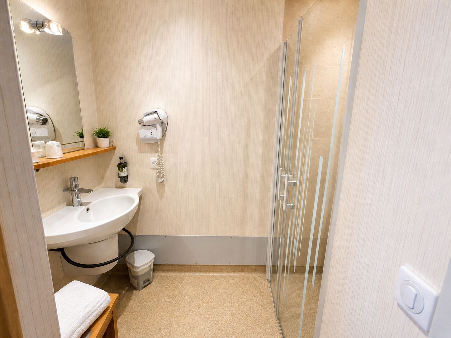 A bathroom with a sink, mirror, towel rack, and a glass shower enclosure.