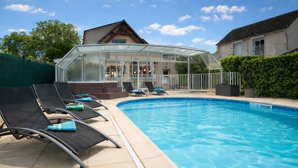 A swimming pool with lounge chairs and a glass-enclosed structure.