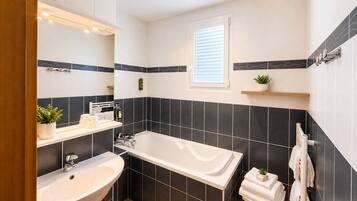 Un baño moderno con bañera, lavamanos y ventana.