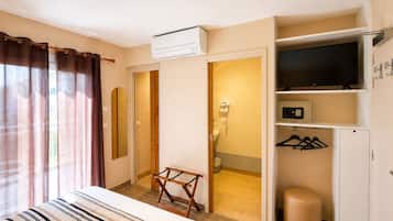 A hotel room with a bed, a wardrobe, a television, a mirror, and a bathroom visible through an open door.
