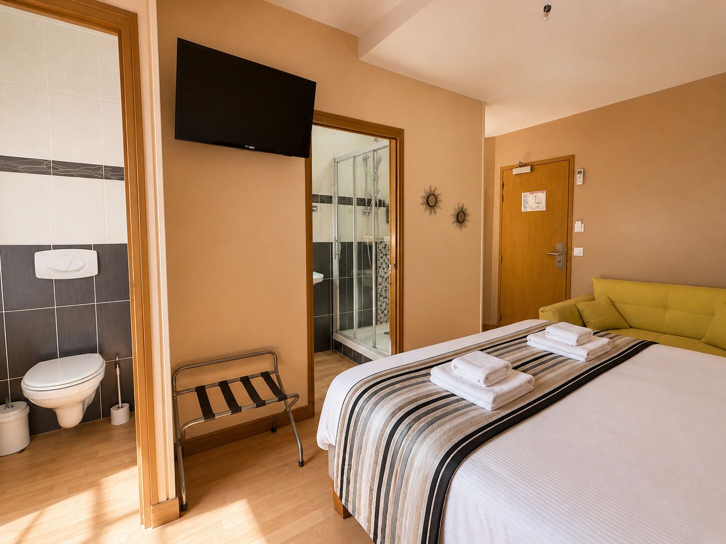 Una habitación de hotel con cama, televisión, ducha y baño.