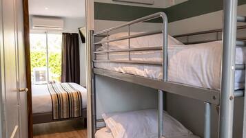 A bunk bed room with a wooden floor, a door leading to a balcony, and a window.