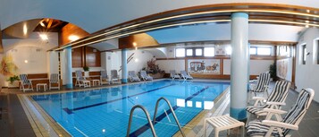 Una piscina techada, sillones reclinables de piscina