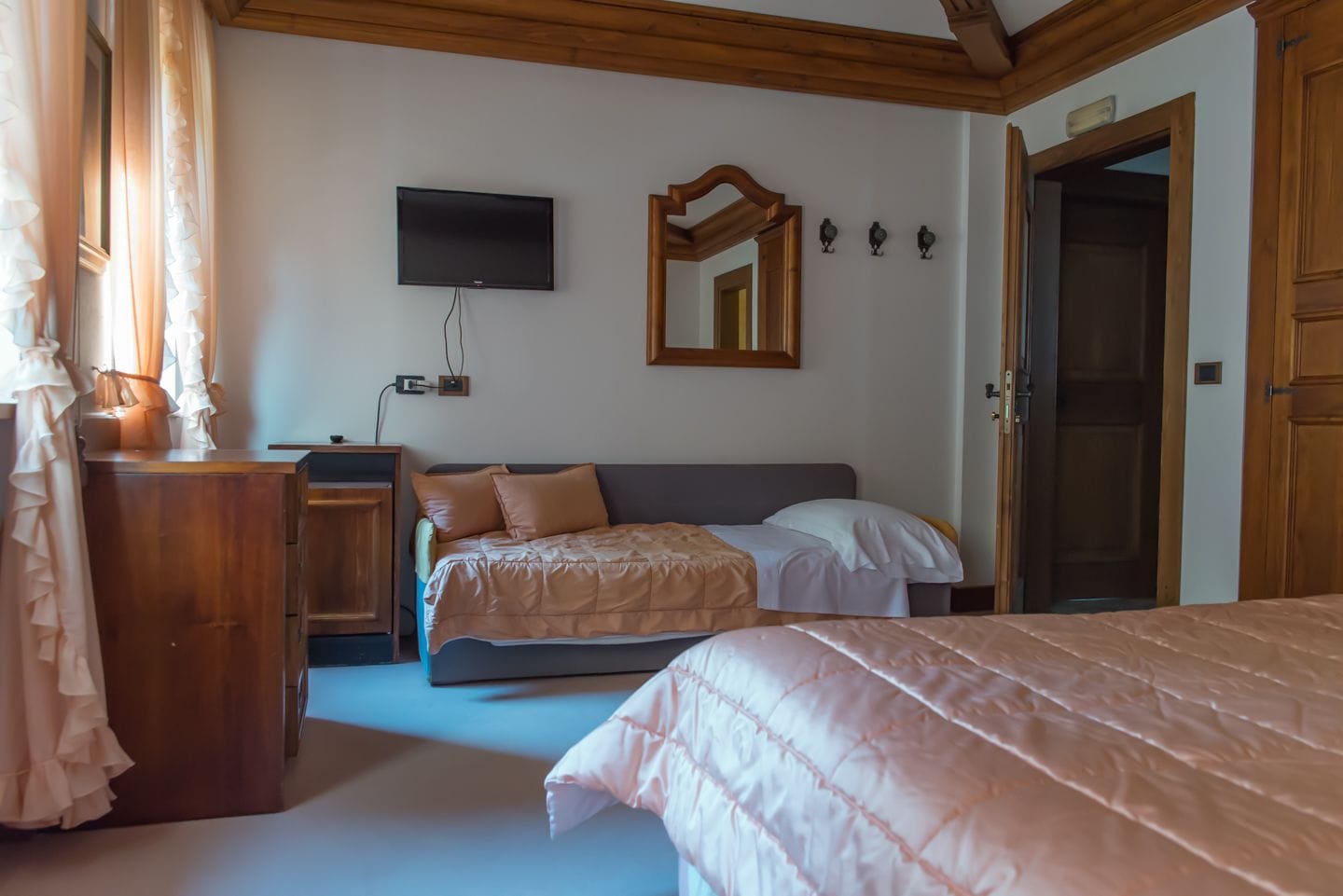 Ein Schlafzimmer mit Bett, Kommode, Fernseher und Spiegel.