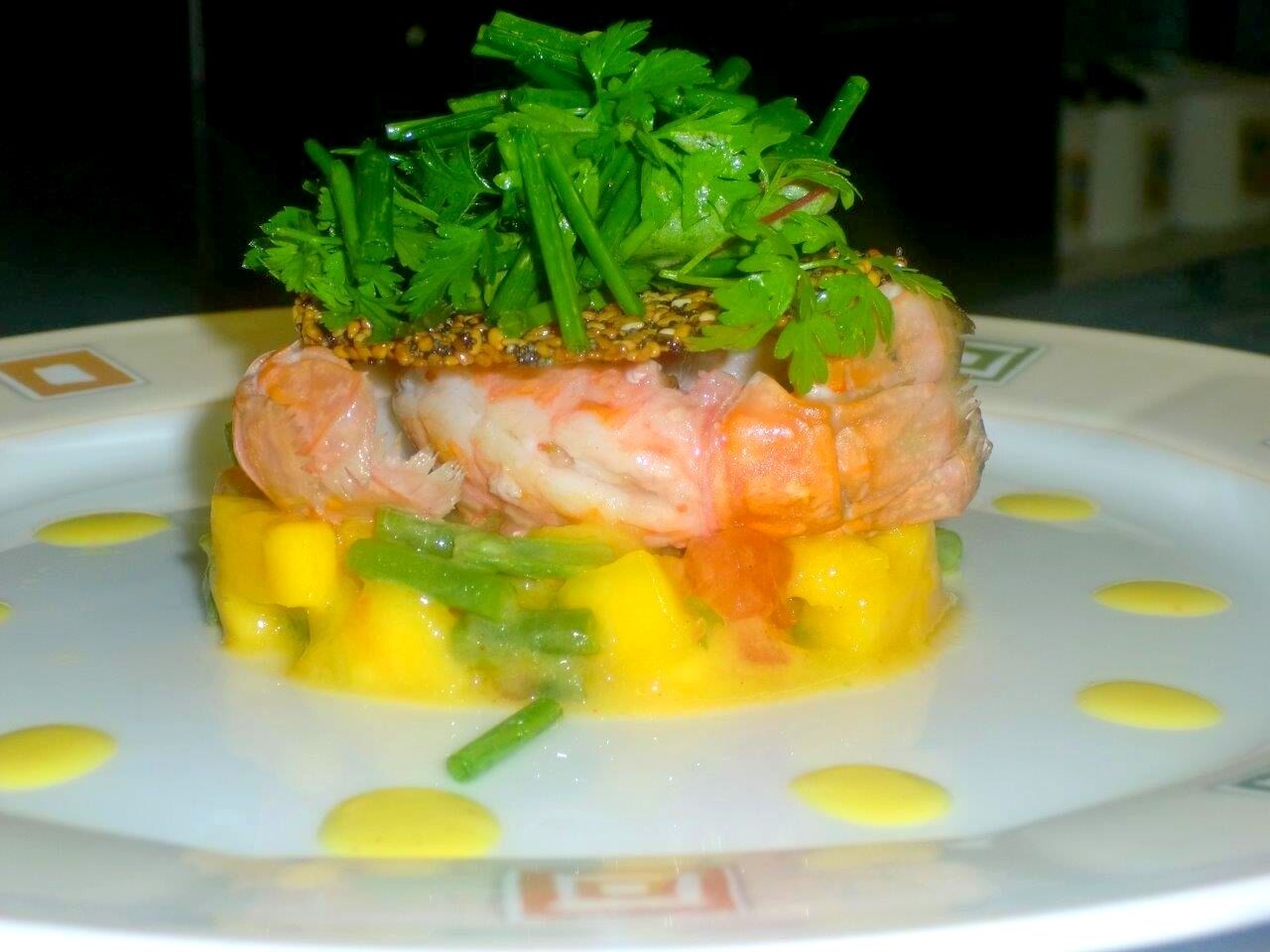 Un plato con camarones, mango y verduras verdes.