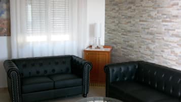 Suite junior, balcón | Área de sala de estar | Televisión de 22 pulgadas con canales digitales