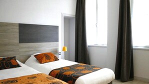 A hotel room with two beds, a large window with curtains, and a modern headboard.