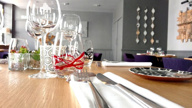 A dining table set with clear glassware, a red decorative item, and a patterned plate.