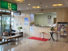 Un área de recepción con mostrador, banco, felpudo rojo y pared con un calendario y carteles informativos.