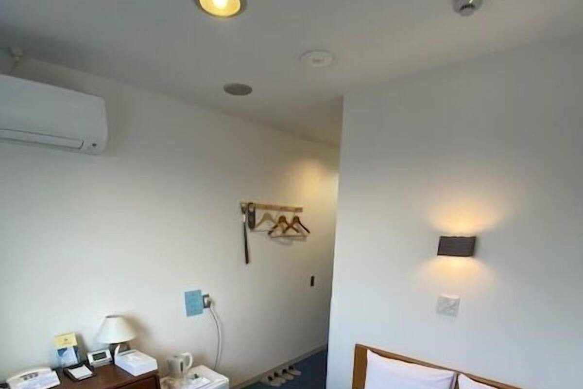 Ein Hotelzimmer mit einem Bett, einem Schreibtisch, einem Sessel, einem kleinen Tisch, einem Wandheizkörper und einer Wandleuchte.