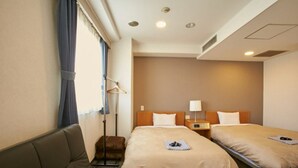 A hotel room with two beds, a sofa, a bedside table, a lamp, and a hanging coat rack. - Hotel New Yutaka (Izumisano)