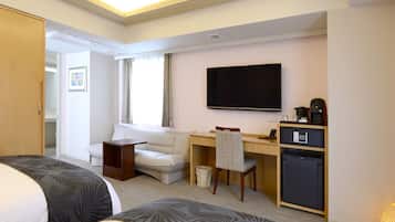 A hotel room with a bed, a desk, a chair, a TV, a mini-fridge, and a wardrobe.