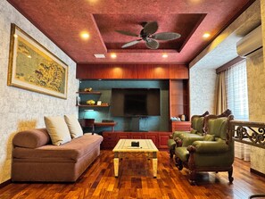 Una sala de estar con sofá, sillones, una mesa de centro, televisor y ventilador de techo.