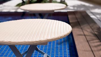 A poolside area with wicker tables and a wooden deck.