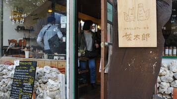 Un letrero de madera con caracteres japoneses, una pared de piedra y un panel con la carta de un café.