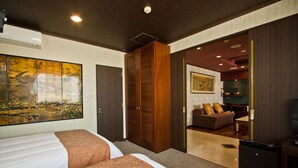 Habitación de hotel con dos camas, un cuadro grande, un armario y una sala de estar con sofá y televisor.