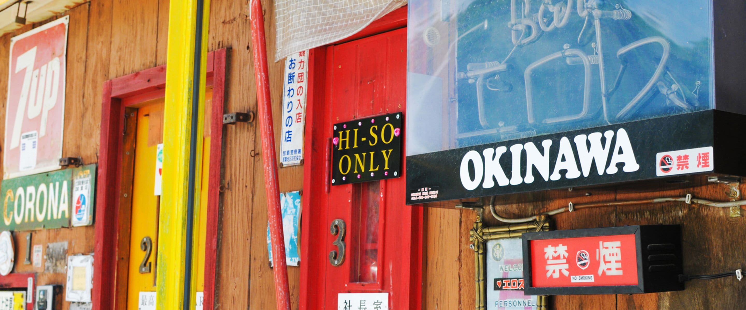 A building facade with multiple signs, including a prominent 'OKINAWA' sign and a 'HI-SO ONLY' sign.