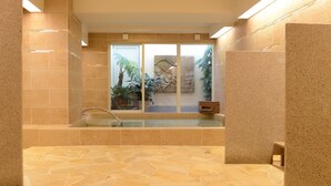 Un baño moderno con suelo de piedra, ducha con cerramiento de vidrio y bañera.
