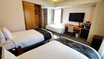 A hotel room with two beds, a desk, a chair, a television, and a wardrobe.