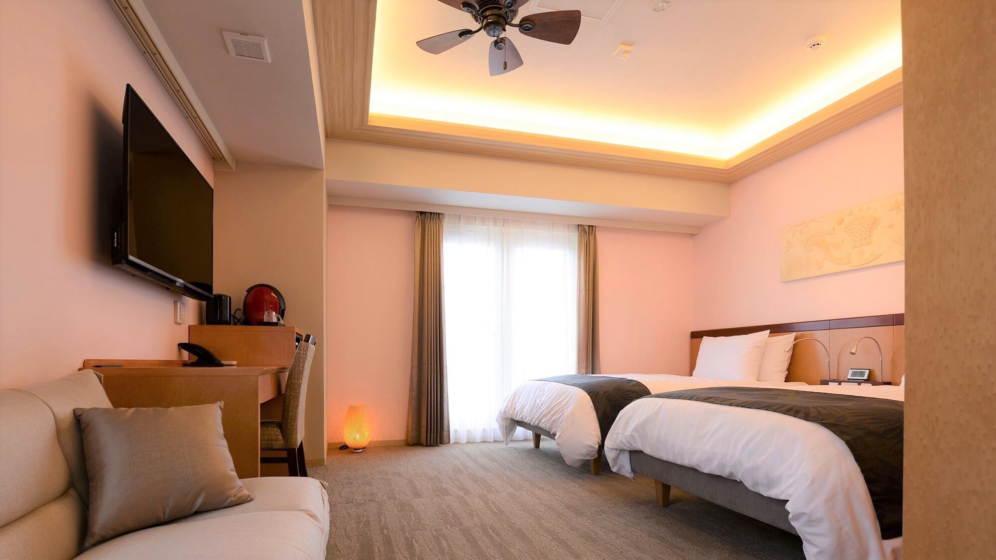 A hotel room with a bed, a desk, a TV, and a ceiling fan.