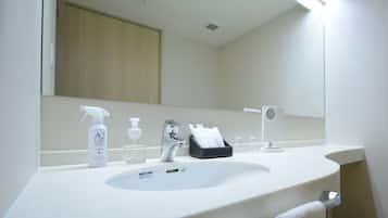 A bathroom with a white sink, a mirror, a faucet, and toiletries.
