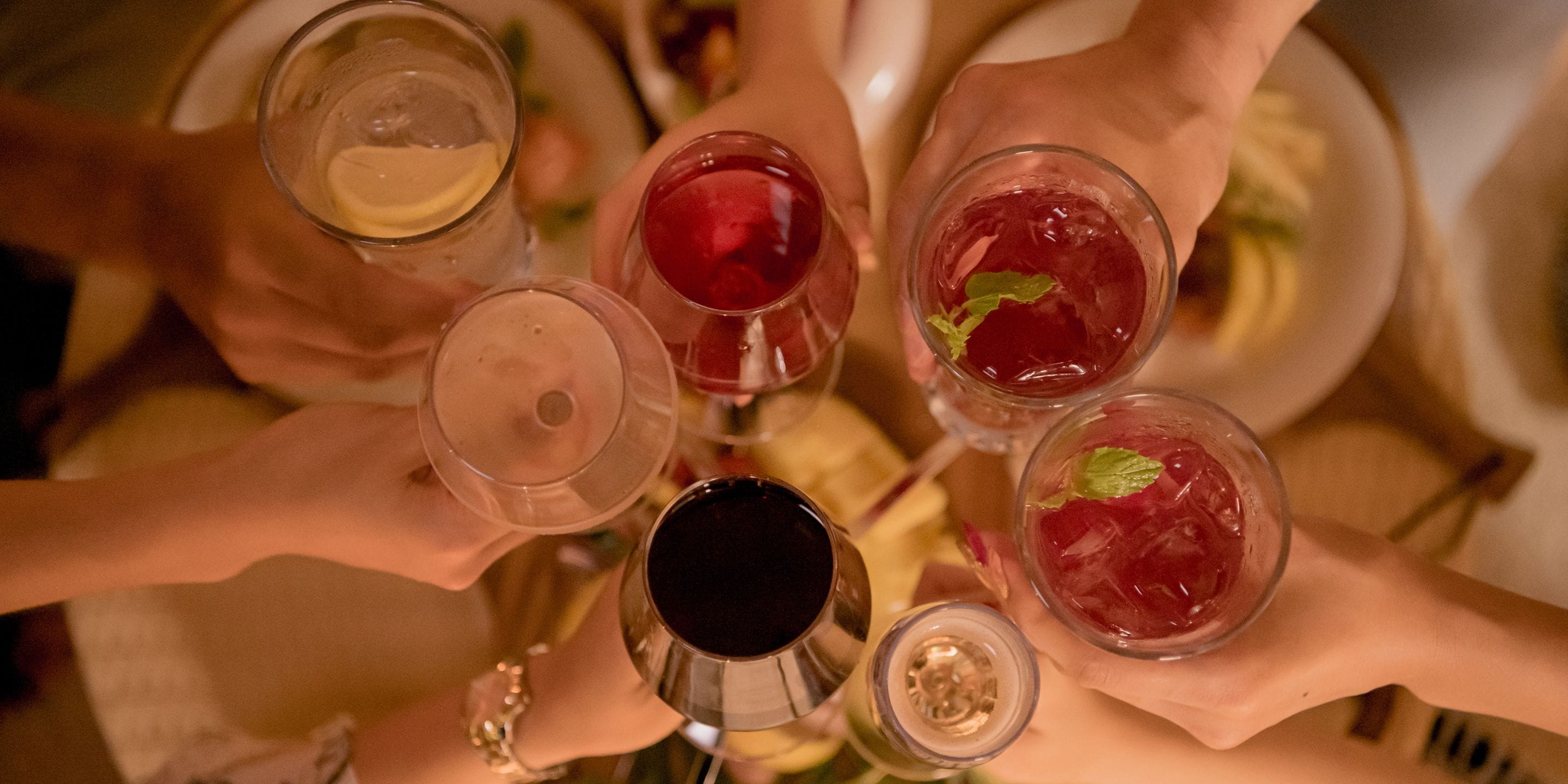 Un grupo de personas sosteniendo diferentes vasos con bebidas, probablemente en un encuentro social o evento.