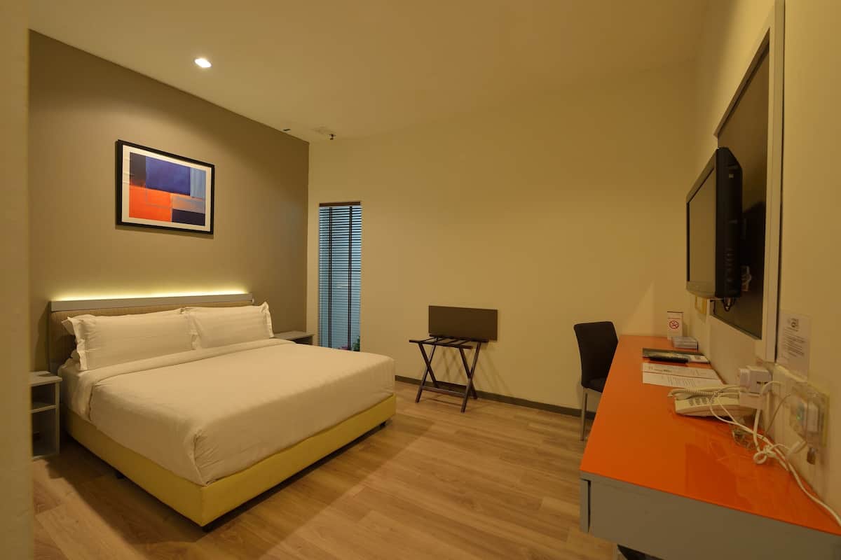 Habitación de hotel con una cama, un escritorio con computadora, un televisor y un cuadro en la pared.