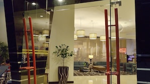 A modern lobby with a glass partition, red vertical elements, and a central plant. - Abell Hotel Kuching (Kuching)