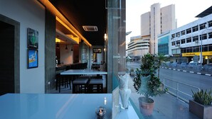 A restaurant with a modern interior, large windows, and a view of the cityscape. - Abell Hotel Kuching (Kuching)