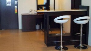 A modern hotel lobby with a wooden floor, a reception desk, two white bar stools, and a large mirror above the desk. - De Garden Hotel (Butterworth)